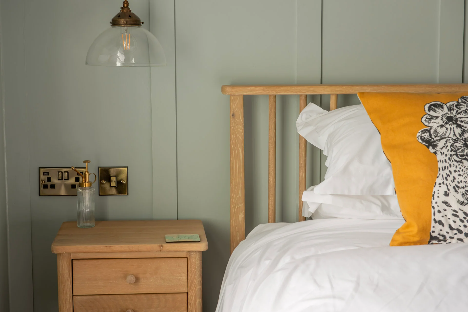 Commercial interior photography by Thinksay — beautifully styled hotel bedroom with sage green panelled walls, warm oak furniture and quality linens.